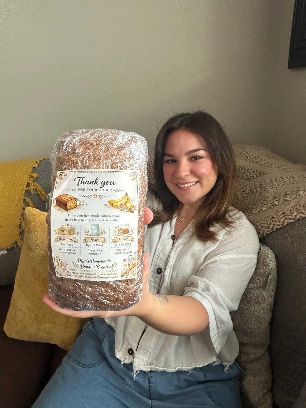 Mya smiling and holding a wrapped loaf of homemade banana bread